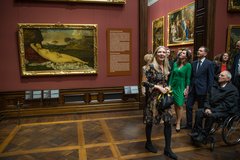 Personen besichtigen Gemälde in einer Ausstellung