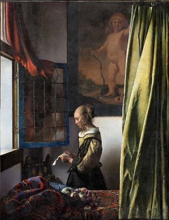 Frau steht am Fenster eines Schlafzimmers und liest einen Brief