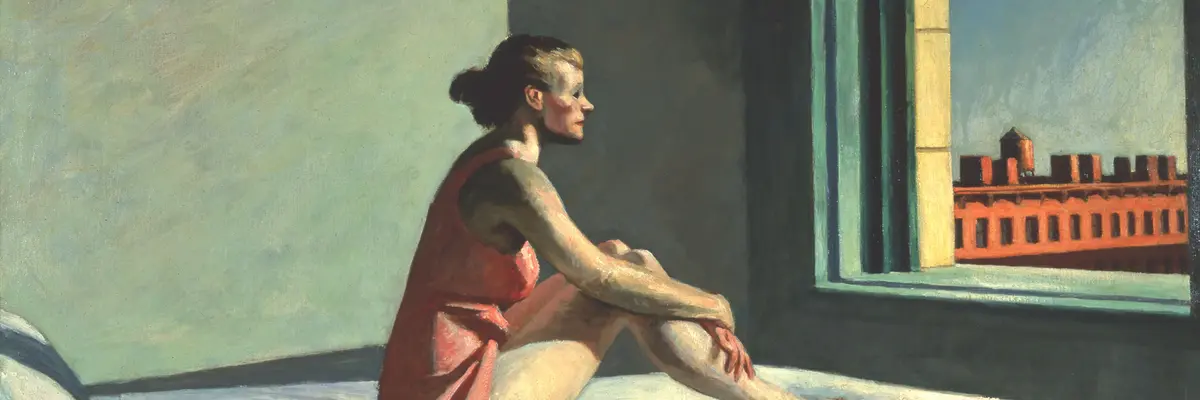 Eine auf einem Bett sitzende, leichtbekleidete Frau schaut aus dem Fenster vor ihr