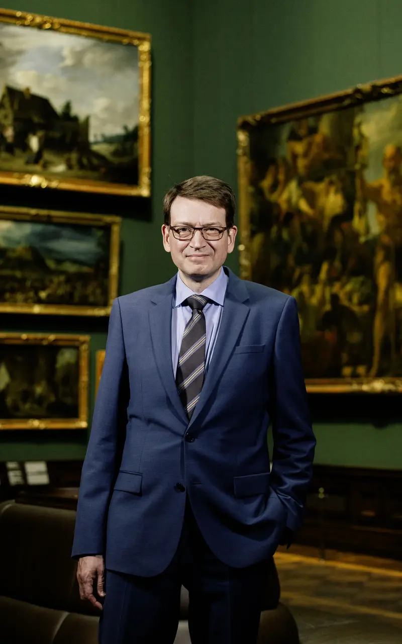 Mann im Anzug mit Gemälden im Hintergrund