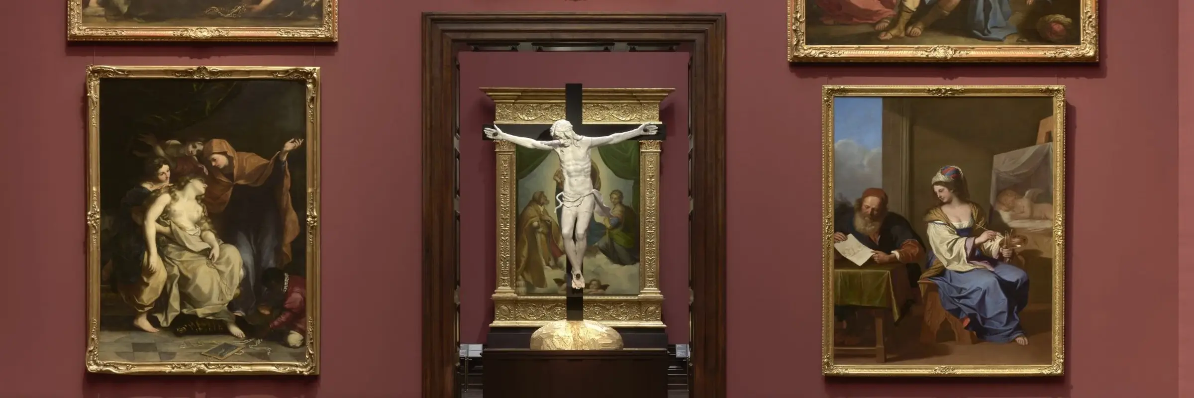 Eine Ausstellungsansicht, in der Ein Kruzifix dem Gemälde "Sixtinische Madonna" von Raffael steht