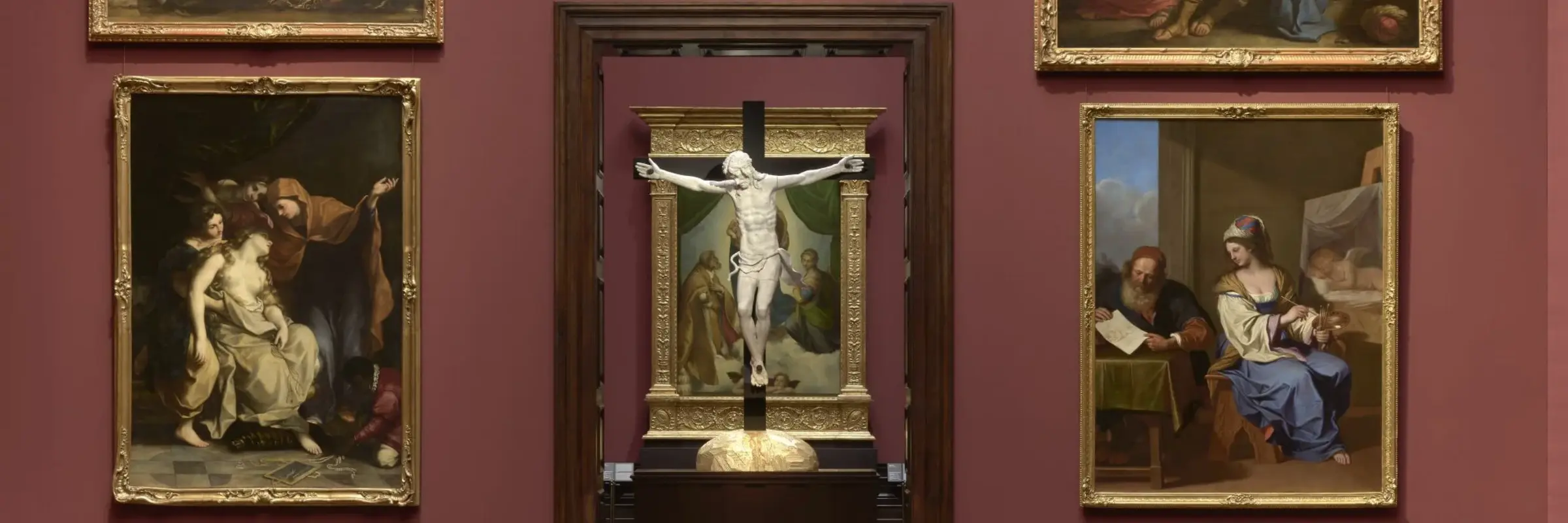 Eine Ausstellungsansicht, in der Ein Kruzifix dem Gemälde "Sixtinische Madonna" von Raffael steht
