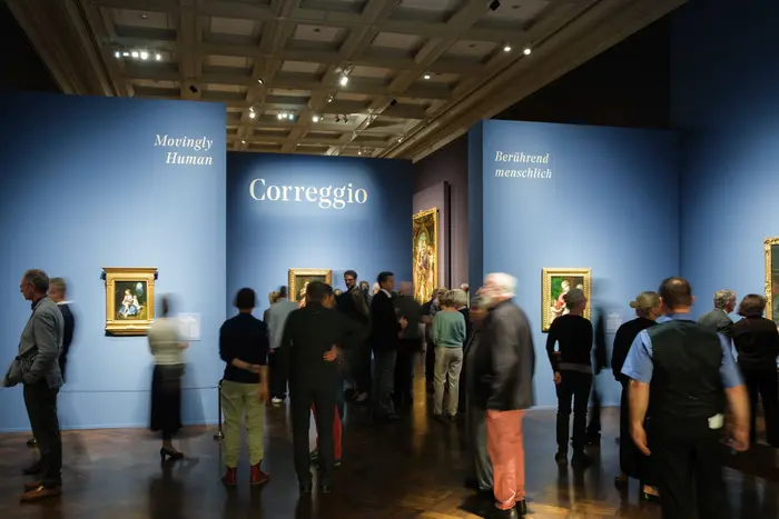Menschen in einem Ausstellungsraum mit Gemälden an der Wand