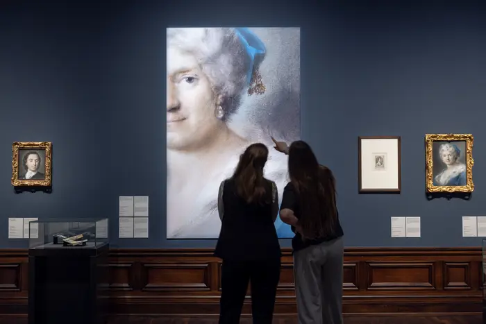 Zwei Besucherinnen schauen sich eine Projektion des Porträts der Künstlerin Rosalba Carriera
