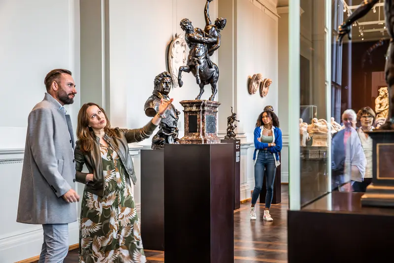 ein Mann und eine Frau schauen sich eine Skulptur in einem Museumsraum an