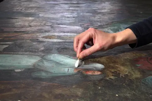 Hand mit einem Wattestäbchen auf einer Leinwand