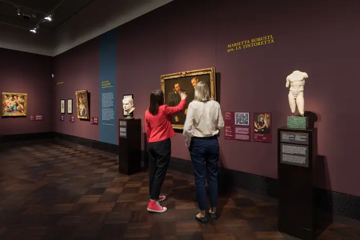 Zwei Besucherinnen stehen vor einem Gemälde und diskutieren 
