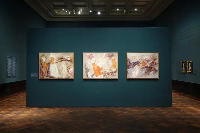 Eine Ausstellungsansicht mit einer Gemäldegruppe, die das Schokoladenmädchen im abstrakten Stil darstellen. 