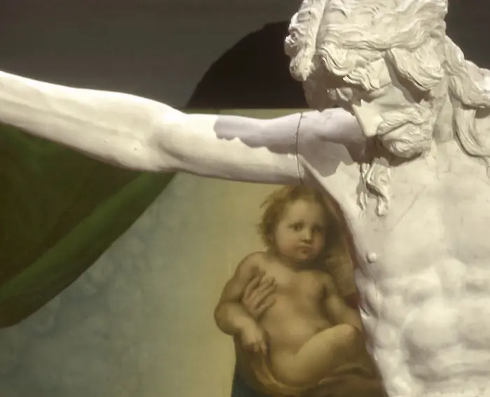 Ein Kruzifix vor dem Gemälde "Sixtinische Madonna" von Raffael