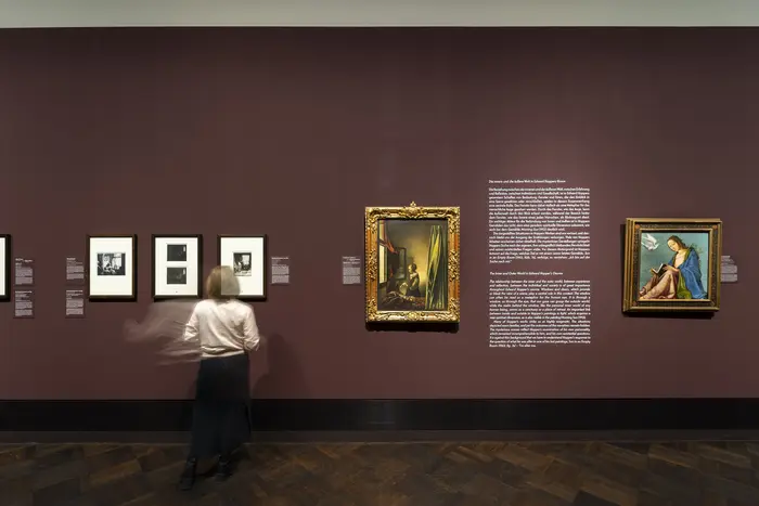 Eine Besucherin schaut sich kleine Bilder an der Wand