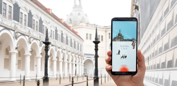 Eine Hand hält ein Smartphon, das die App "Bellotto Click" zeigt