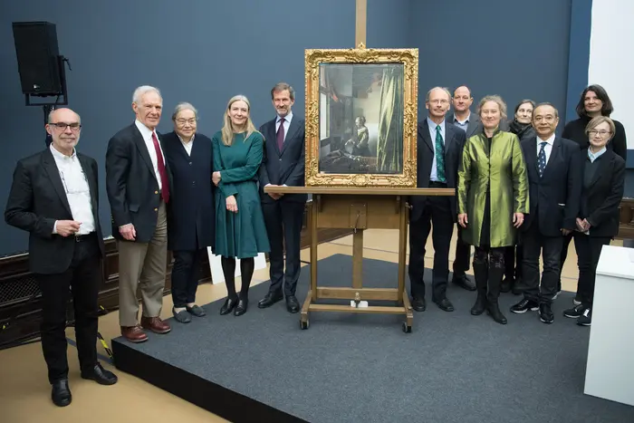 Ein Gruppenfoto, auf dem Museumsmitarbeiterinnen und Museumsmitarbeiter neben dem Gemälde "Briefleserin am offenen Fenster" stehen.  