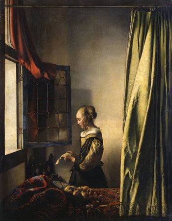 Frau steht am Fenster eines Schlafzimmers und liest einen Brief